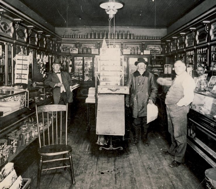 Oswald's Pharmacy interior in 1897. Wood floors, wood cabinets. Glass cases line the walls, filled with various medicinal remedies.