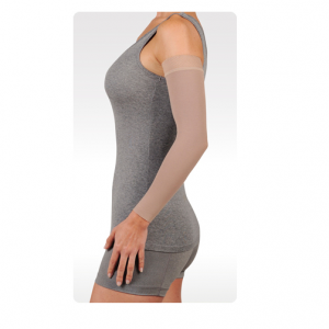A female arm model wearing the Juzo dynamic arm compression sleeve. The sleeve is tan and stretches from her wrist to shoulder.