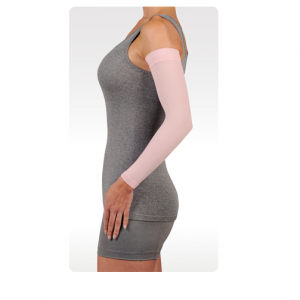 A female arm model wearing the Juzo soft sleeve arm compression sleeve. The sleeve is pink and stretches from her wrist to shoulder.