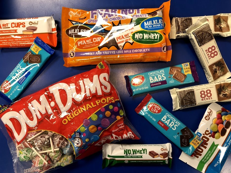 A large selection of the allergy-friendly candy available at Oswald's for Halloween 2018. Spread across a blue table.