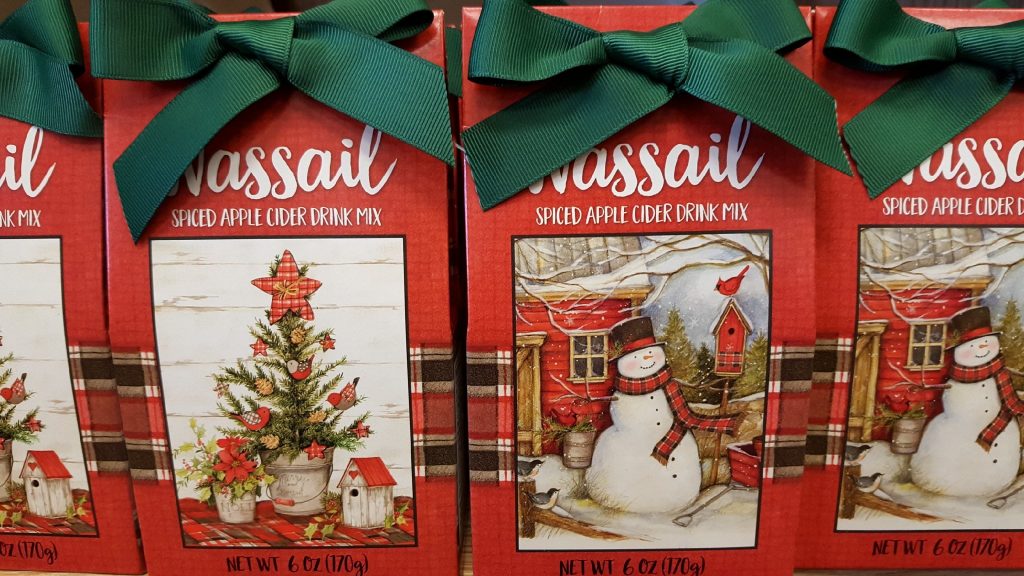 Closeup of a row of Wassail Cider. 4 Holiday themed boxes on a shelf in Oswald's Christmas gift section.