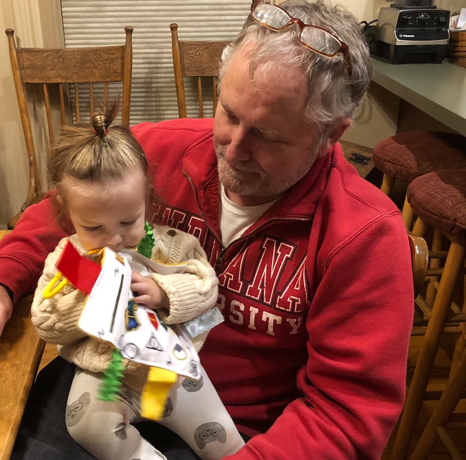 Picture of Oswald's owner Bill Anderson with his grandson Arlo Sitting on his lap. Arlo is playing with a Baby Jack Lovey.
