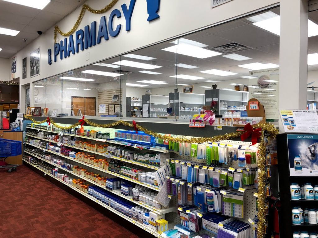 The Pharmacy counter at Oswald's Pharmacy. Hundreds of different vitamins stocked on a shelf underneath the pharmacy window. 