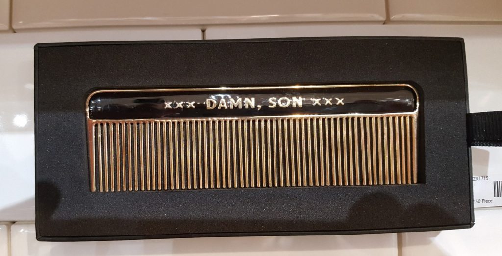 A gold and black metal comb with the phrase 'damn son' printed on it.