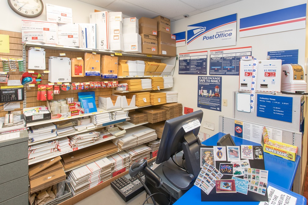 Post Office located in Oswald's Pharmacy. A shot of the post office checkout counter with many USPS signs and envelopes for shipping.