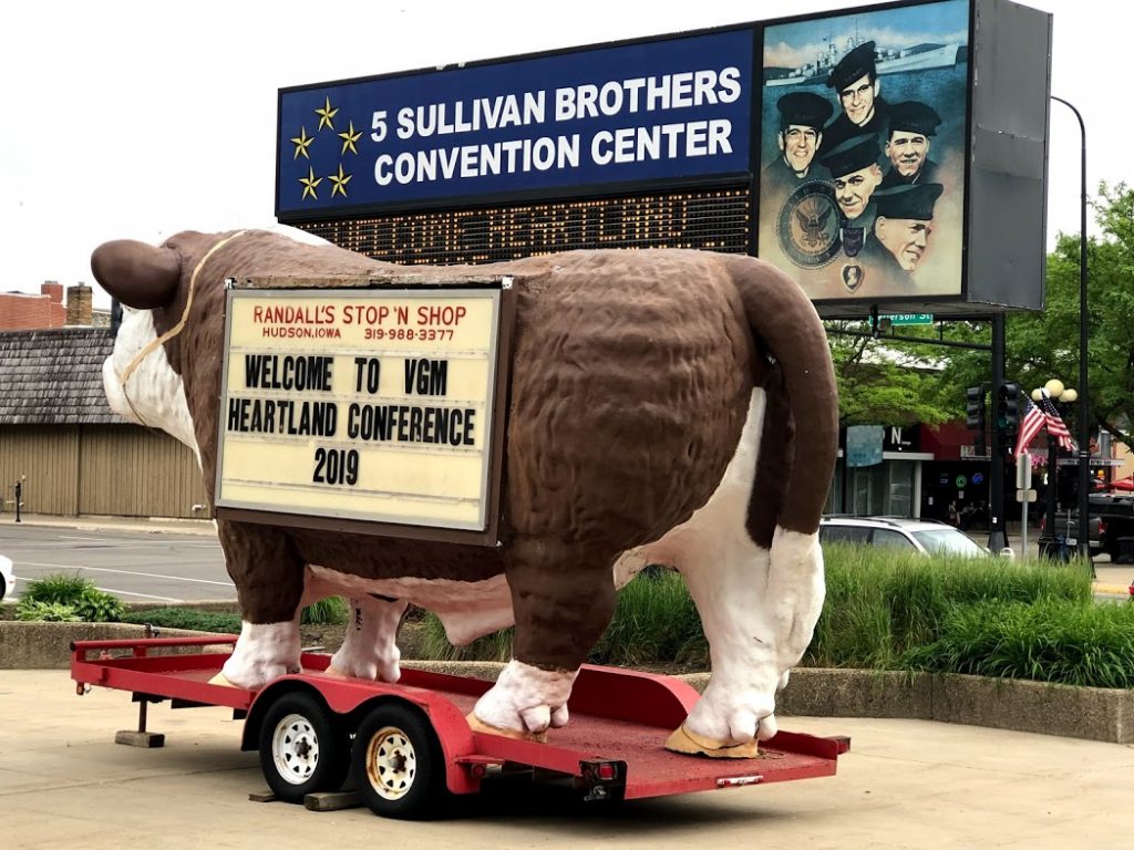 A cow float trailer outside the 5 Sullivan Brothers Convention Center in Waterloo, Iowa. A sign on the cow welcomes guests to the 2019 VGM Heartland Conference.