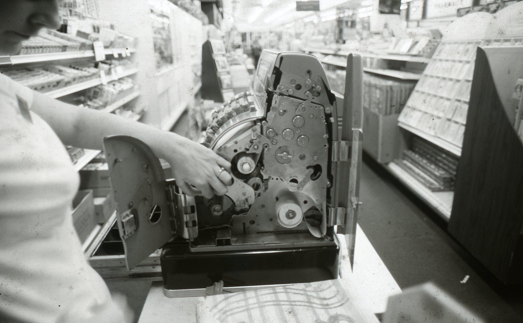 An image of an old register from the 1940s. The side of the register is open, showing the gears and cogs inside the register. The picture was taken at Oswald's in a 1975 store cleanup.