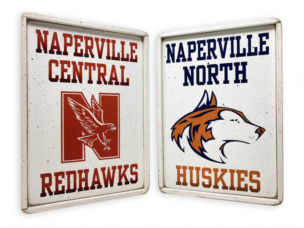 Naperville High School NNHS NCHS Team Signs. Photo of two Naperville high school wooden signs: Left Naperville Central High School with the Redhawks logo, Right: Naperville North High School with the Huskies logo.
