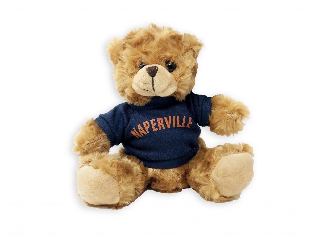 Naperville Pennington Bear. Photo of a stuffed Paddington Bear wearing a Naperville T-shirt, orange letters on a navy shirt.