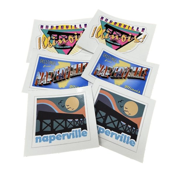 A 6-pack of Naperville-themed vinyl stickers featuring retro, vintage postcard, and Riverwalk bridge designs, exclusive to Oswald’s Pharmacy.