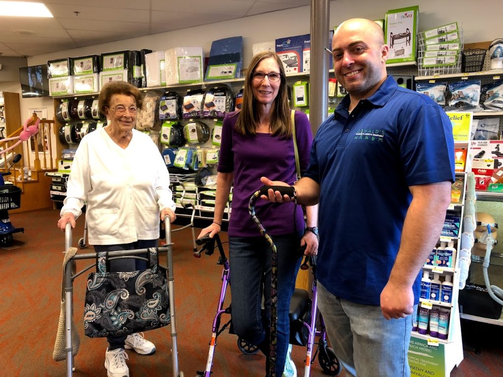 Oswald’s Medical staff member assisting two women with mobility aids inside the showroom, surrounded by medical supplies.