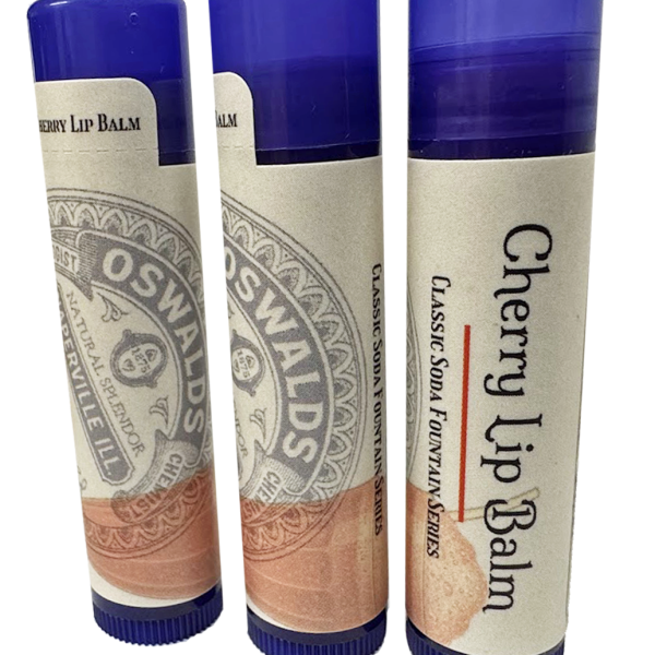Three upright tubes of Oswald’s Cherry Lip Balm with vintage labels and purple caps, showcasing different sides of the packaging.